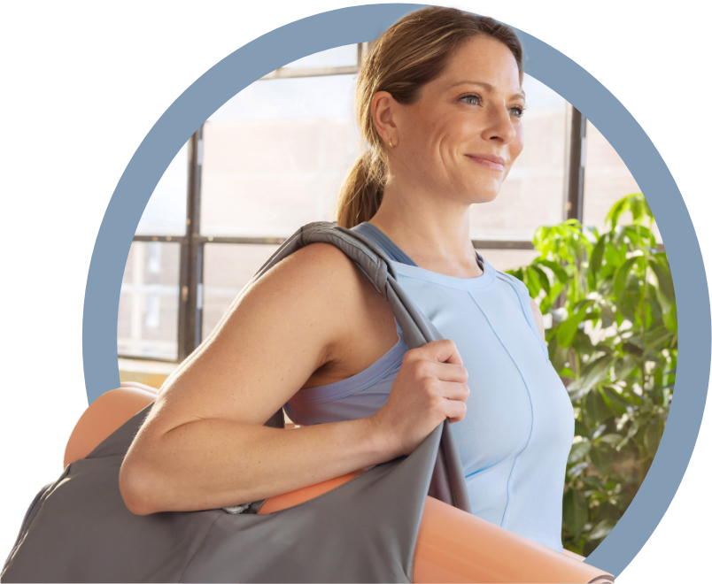 Mujer sonriente cargando una colchoneta y una bolsa de ejercicio