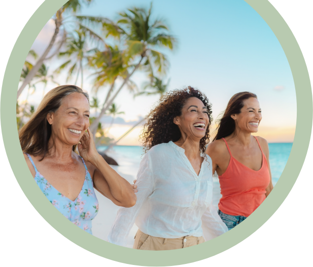 Tres mujeres riendo y caminando juntas en una playa tropical