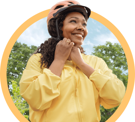 Mujer sonriente abrochándose el casco de bicicleta al aire libre